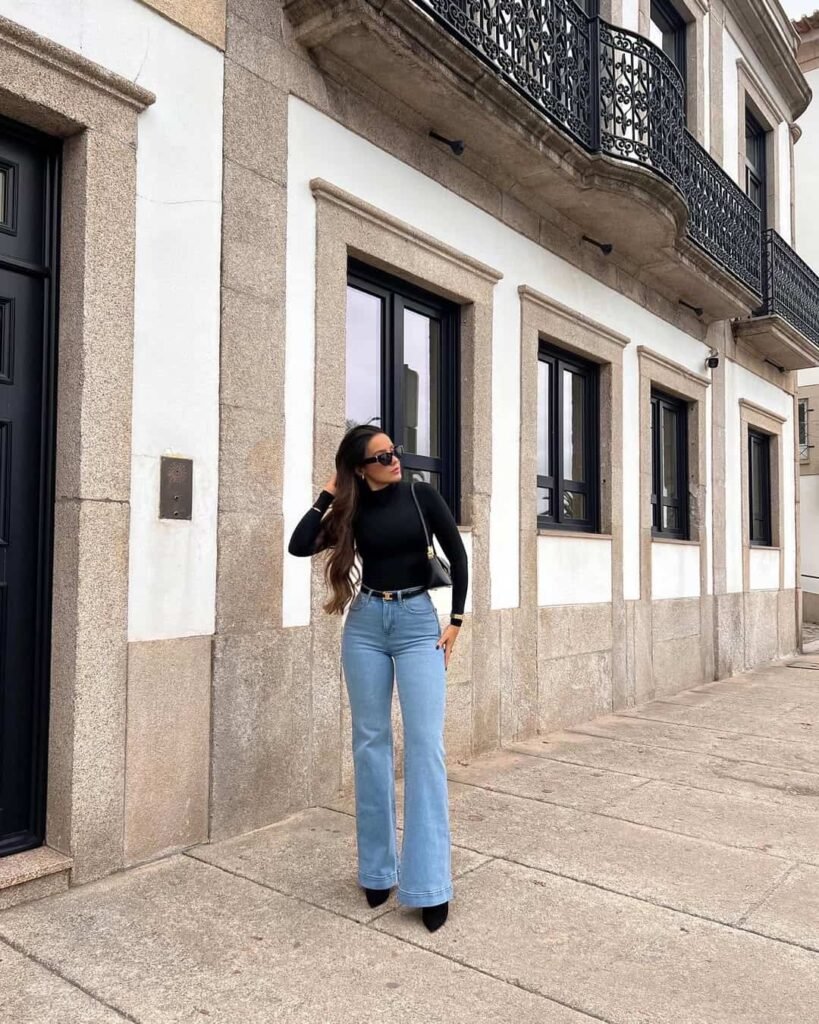 Elegant wide leg pants outfit with light wash flared jeans and a sleek black turtleneck, perfect for a polished city stroll.