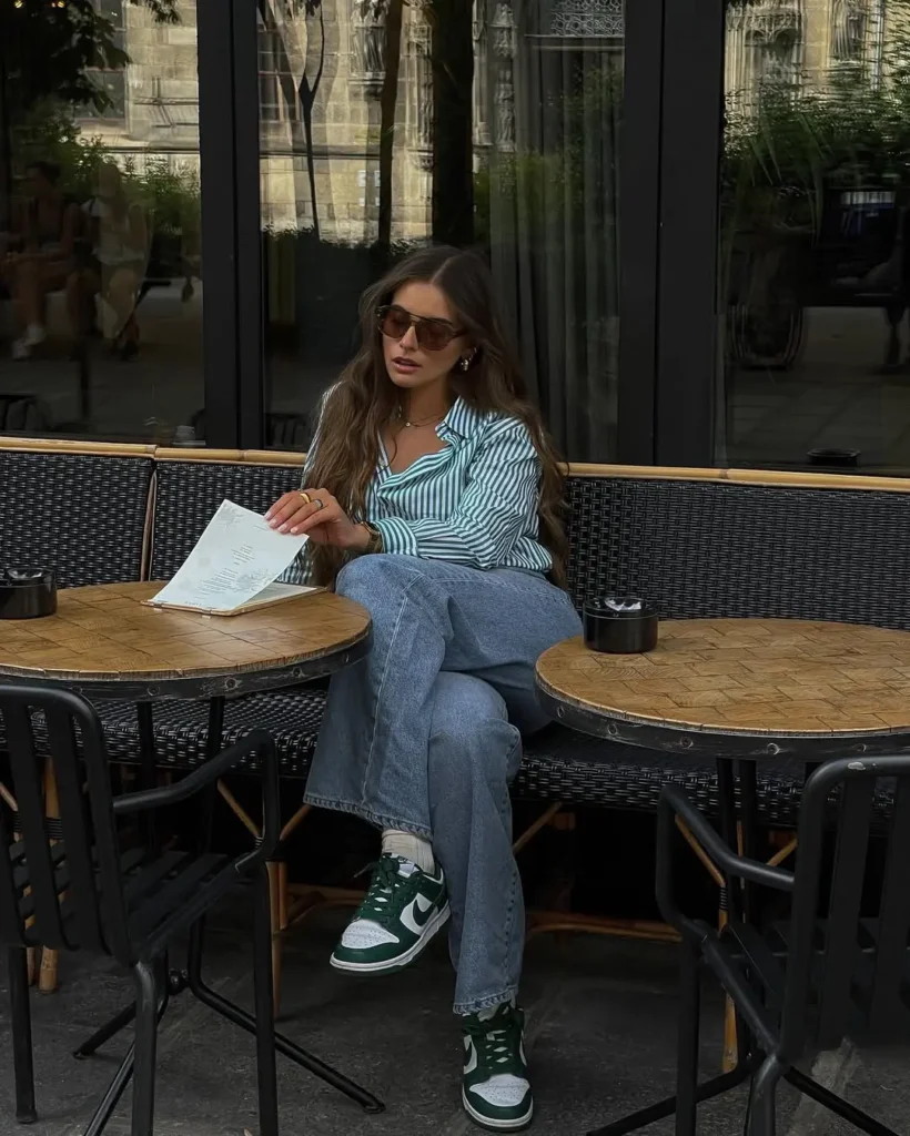 Trendy Casual Summer Outfits with a green-and-white striped button-down shirt tucked into relaxed blue jeans and styled with green Nike sneakers and oversized brown sunglasses.