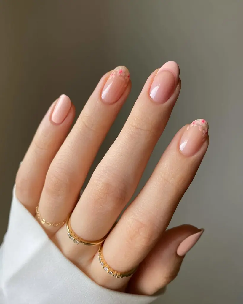 Spring Nail Ideas featuring soft nude pink nails with tiny pink floral confetti on the tips for a subtle spring touch.