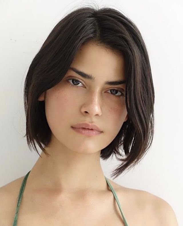 Cute Hairstyles for Short Hair in a sleek and classic chin-length bob with a middle part, highlighting natural black hair and minimal styling.

