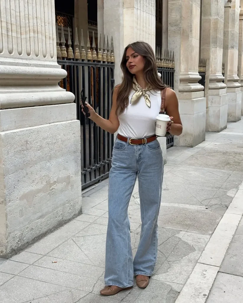 Polished Casual Summer Outfits featuring a white sleeveless top with a silk neck scarf, tucked into high-waisted light blue jeans, styled with tan ballet flats and a brown leather belt.