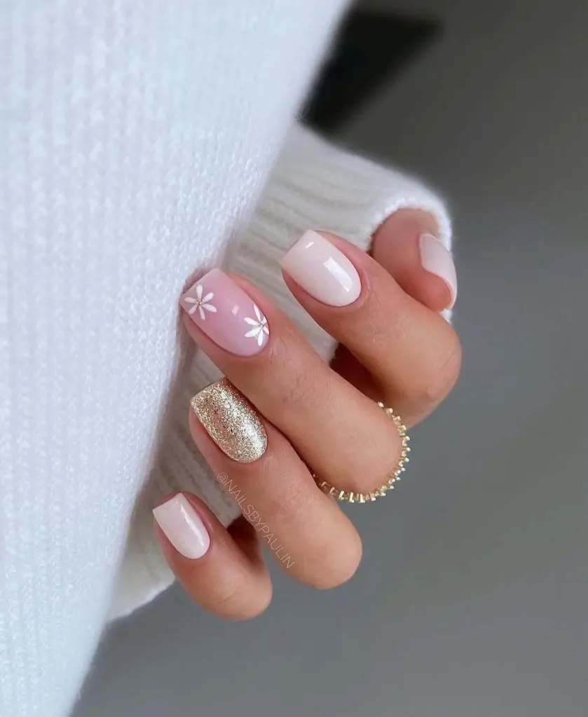 Soft pastel nail ideas featuring daisies, light pink shades, and one glitter accent nail.