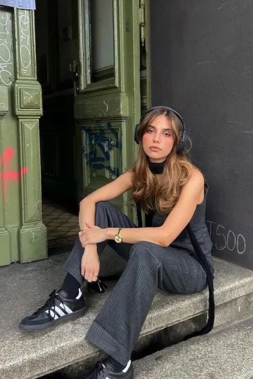 Modern retro vibe with Adidas Samba Outfits, pinstripe trousers, sleeveless top, and large over-ear headphones.