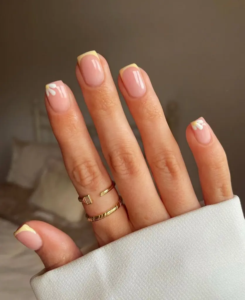Spring Nail Ideas combining yellow French tips with cute white daisy petal accents, giving a fresh spring vibe.