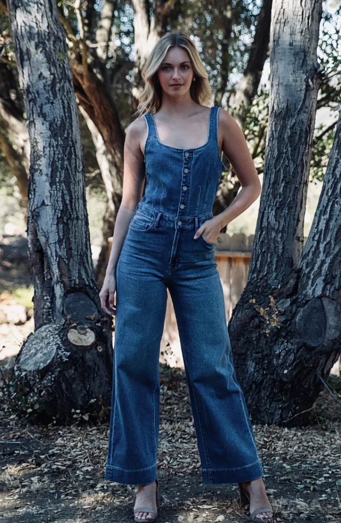 Model standing in a forest setting, dressed in a sleeveless denim jumpsuit with wide legs—an effortlessly cool and modest summer outfit.