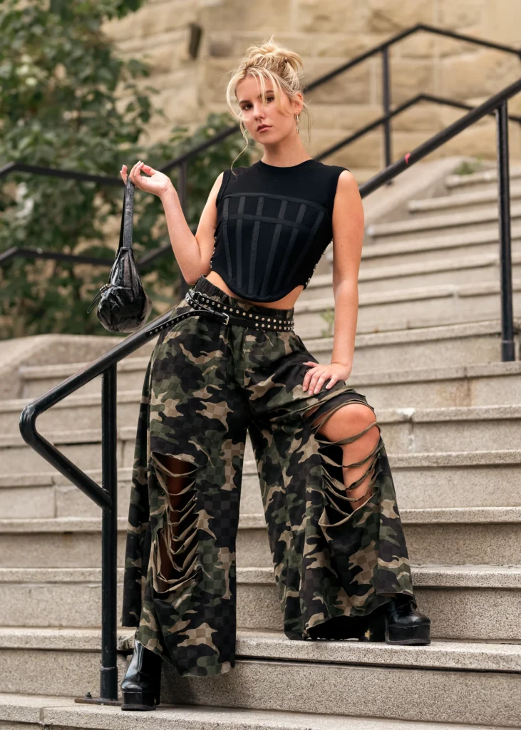 Edgy Camouflage Pants Outfit styled with wide-leg shredded camo pants, a black corset-style tank top, and combat boots.