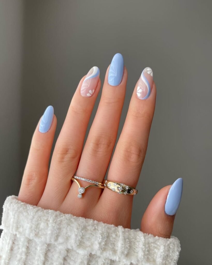 Spring Nail Ideas featuring baby blue swirls with soft floral designs on a translucent nude background.