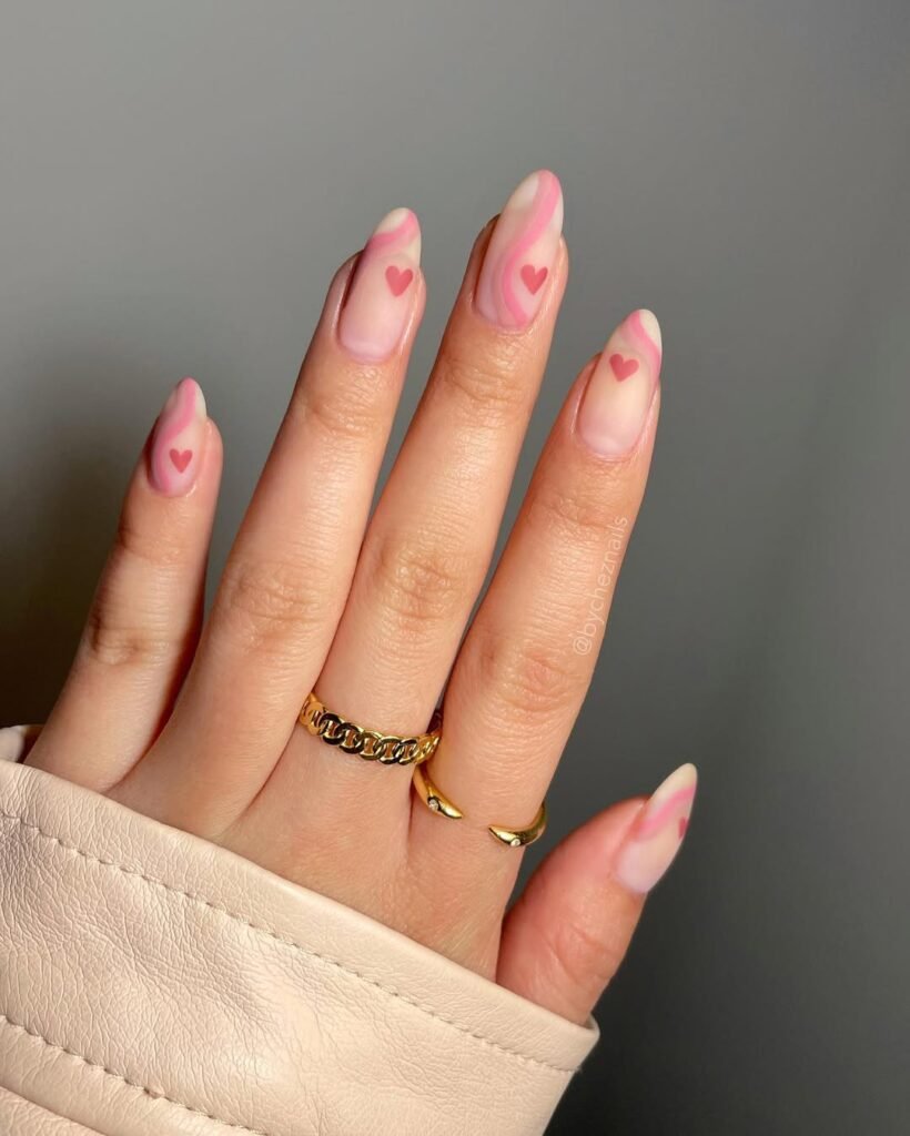 Soft pink and heart-themed nail ideas with abstract swirl accents for a romantic look.