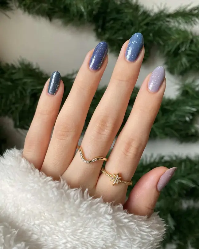 Gradient blue to purple winter nail ideas with a snowy sparkle effect on almond-shaped nails.