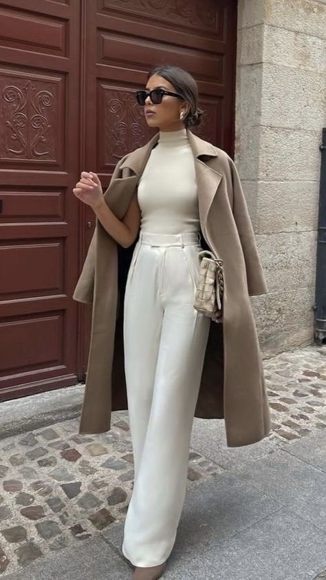  Sophisticated woman in a cream turtleneck, high-waisted white trousers, and camel overcoat for a refined look expensive outfit.