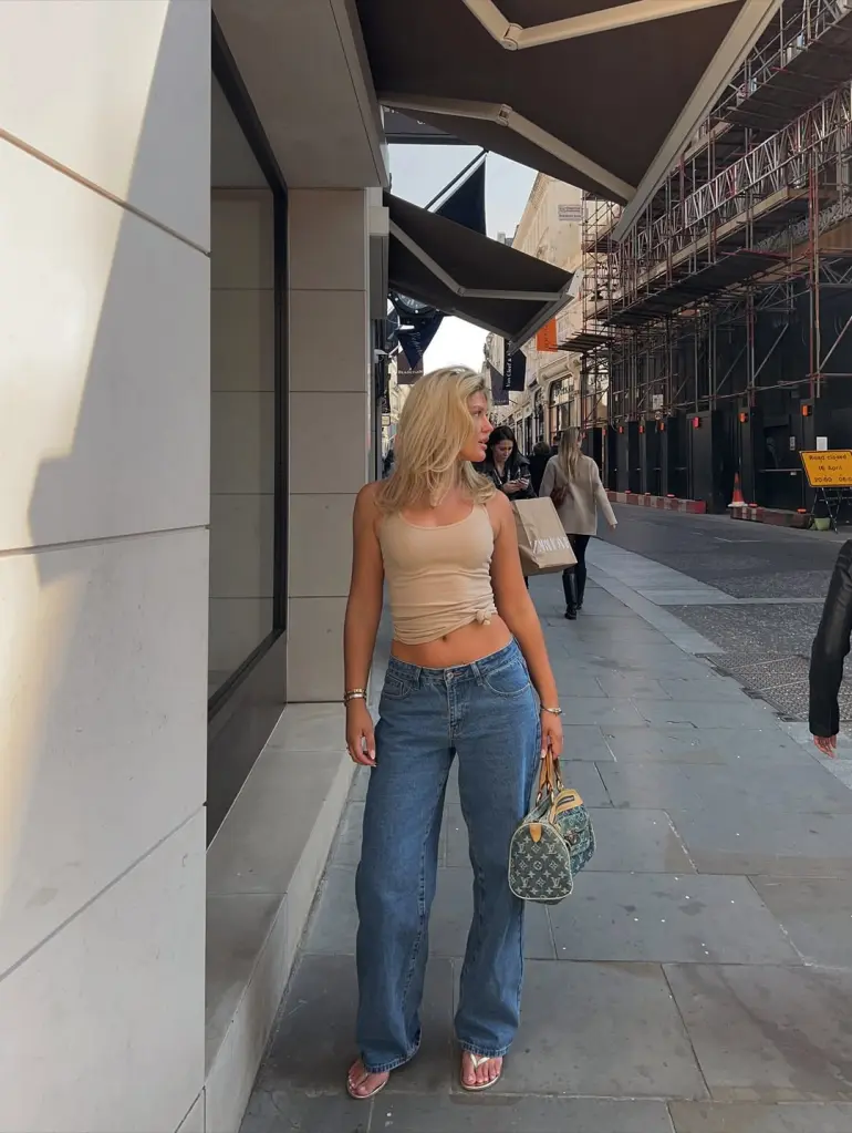 Trendy Casual Summer Outfits look with a beige ruched tank top and relaxed blue jeans, styled with flip-flops and a designer handbag.