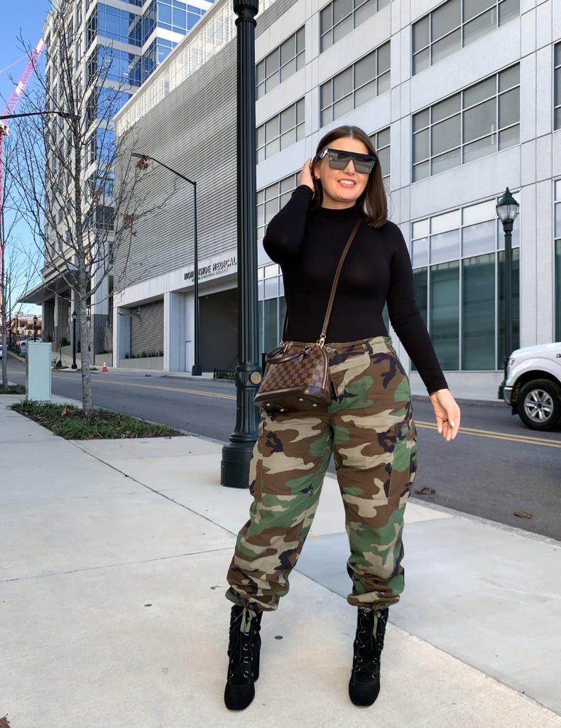 Chic Camouflage Pants Outfit with high-waisted cargo pants paired with a fitted black turtleneck, heeled lace-up boots, and sunglasses.
