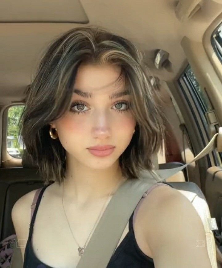 Cute Hairstyles for Short Hair styled with tousled volume, curtain bangs, and subtle highlights for a soft car selfie look.