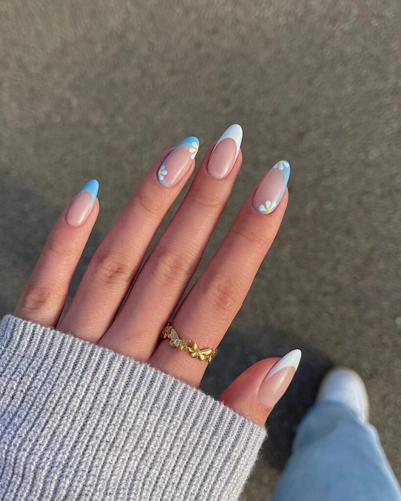 Spring Nail Ideas with blue and white French tips combined with daisy floral accents on a clear nude base.