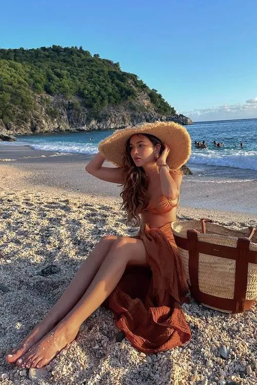 Beach-ready Summer Vacation Outfit with a rust-colored bikini, matching wrap skirt, and oversized straw sunhat.