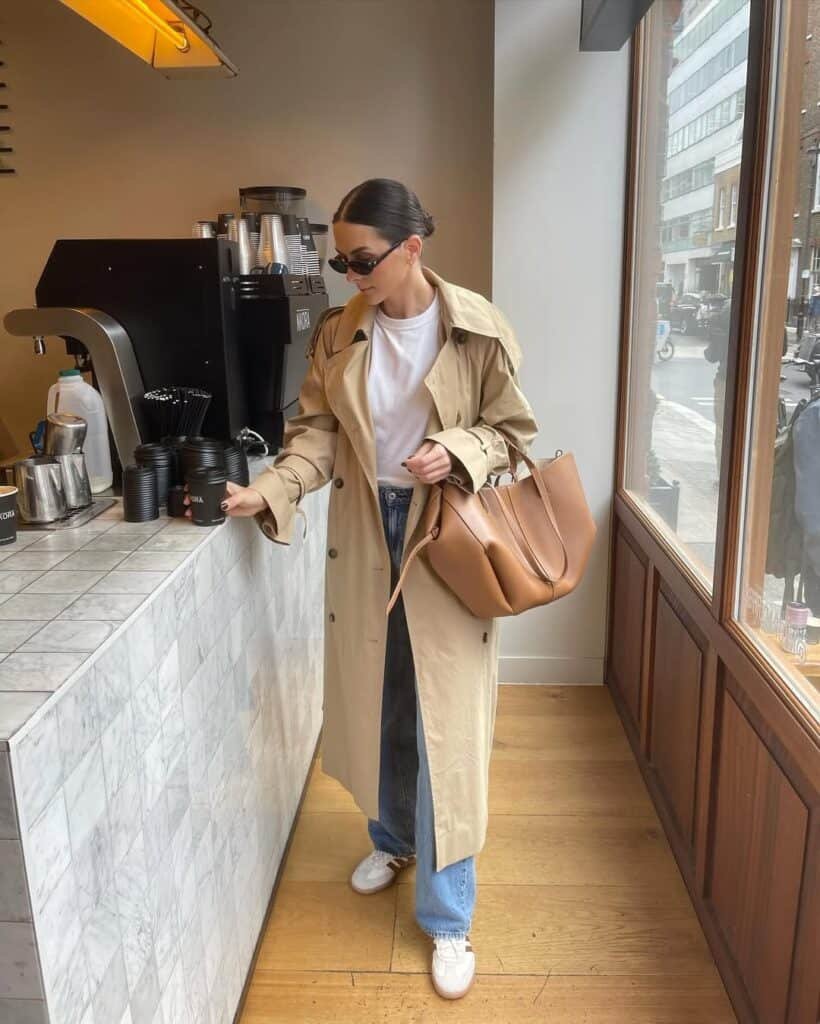 Relaxed sophistication with a beige trench coat layered over jeans and a white tee, styled with sneakers and a structured tote — look expensive outfits.