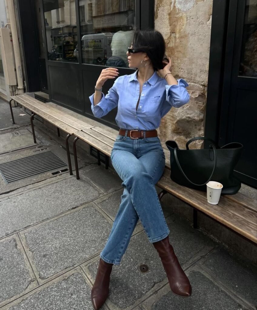 Classic coffee date look with a light blue shirt, high-waisted jeans, brown boots, and minimal accessories.
