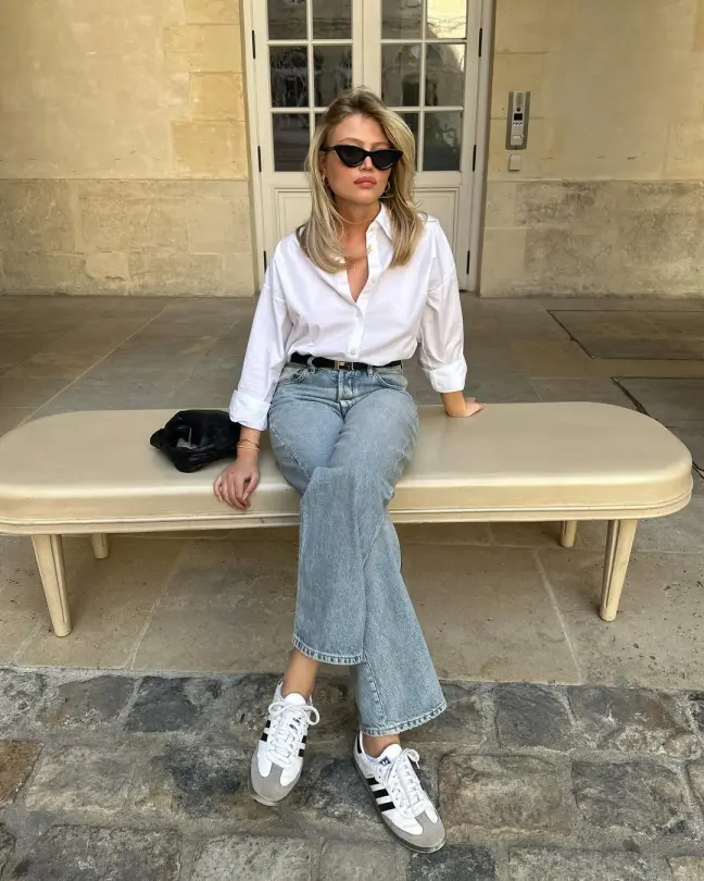 Smart Casual Summer Outfits with a white shirt tucked into light-wash straight jeans and styled with sneakers and cat-eye sunglasses.