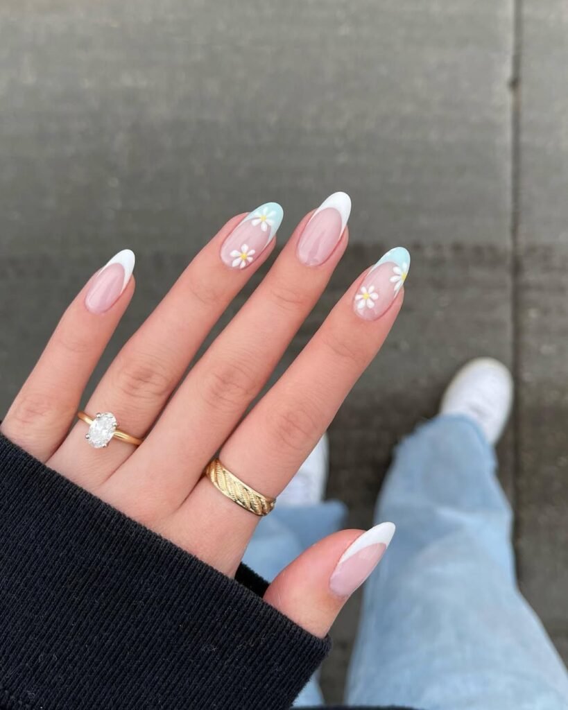 Spring Nail Ideas combining white and baby blue French tips with cute daisy flowers on a glossy nude base.