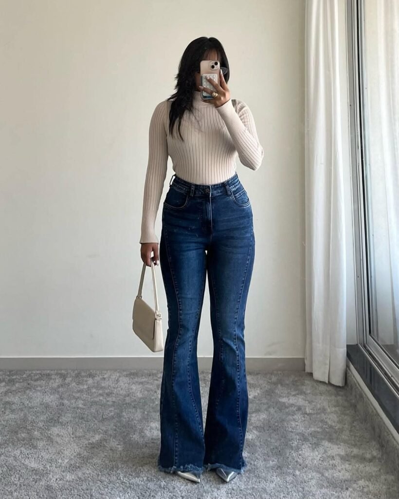 Classy wide leg pants outfit featuring dark denim flares paired with a fitted beige turtleneck and pointed heels.