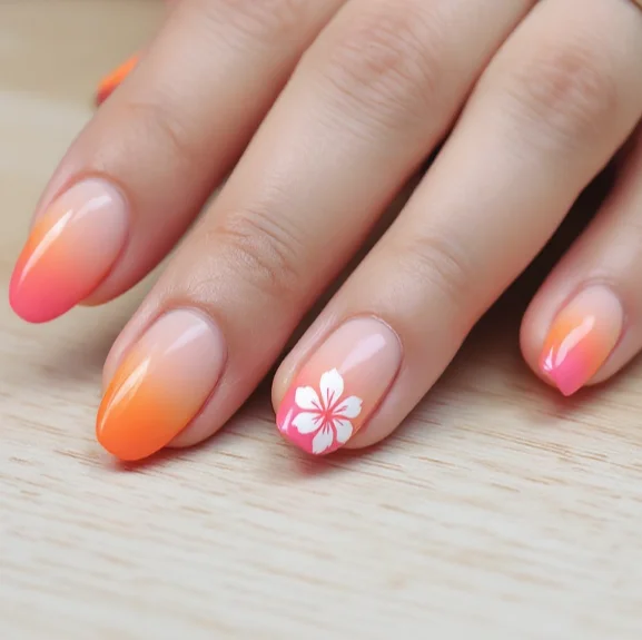 Gradient orange and pink acrylic nails with a white flower accent design.