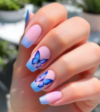 Blue butterfly acrylic nails with ombre blue French tips on a soft pink base.