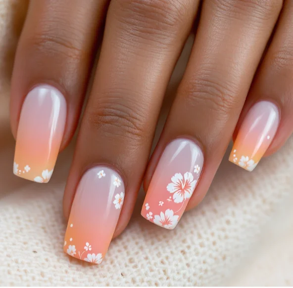 Sunset ombre acrylic nails with white floral detailing for a fresh, tropical vibe.