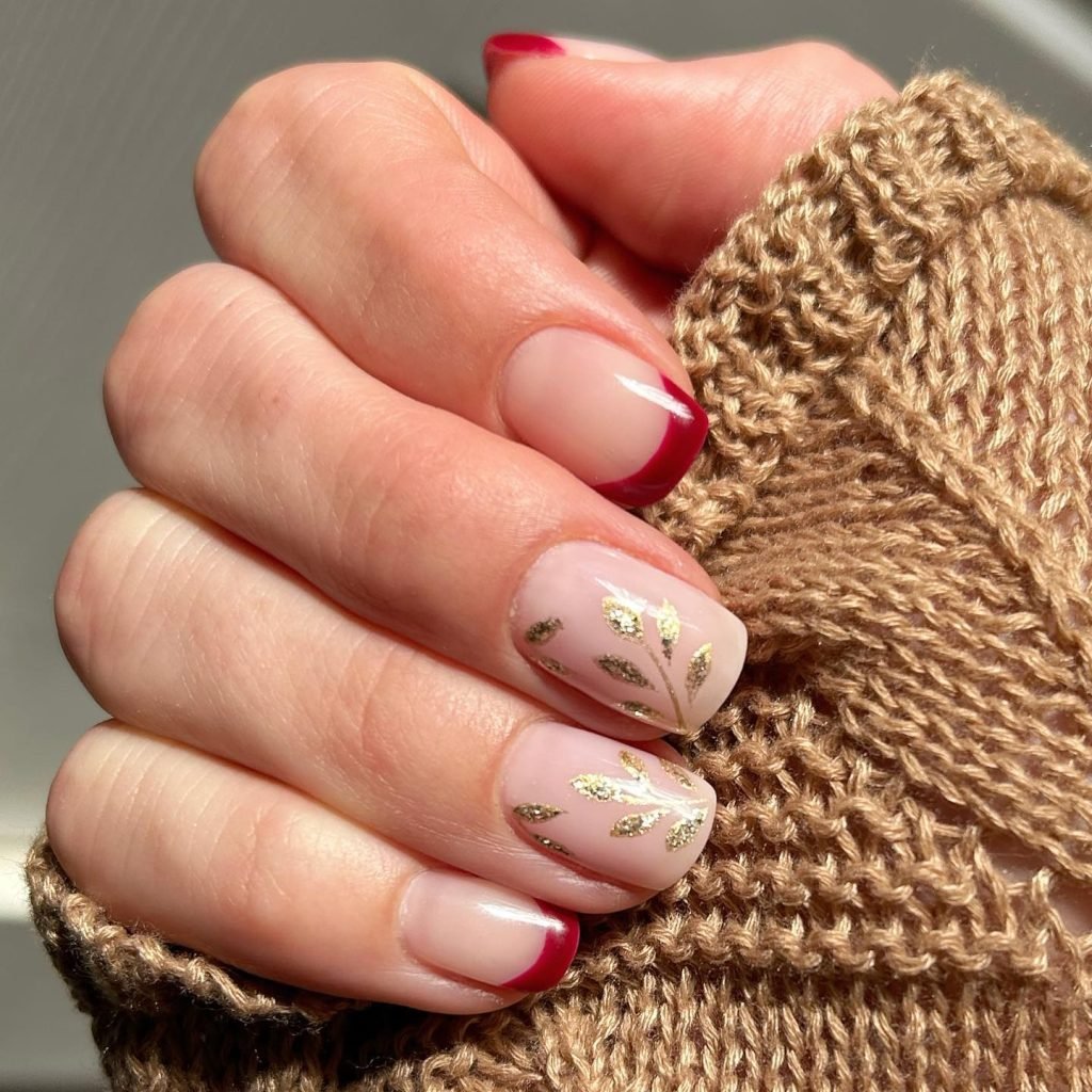 Short fall nail designs with deep red French tips and gold leaf accents on nude base.
