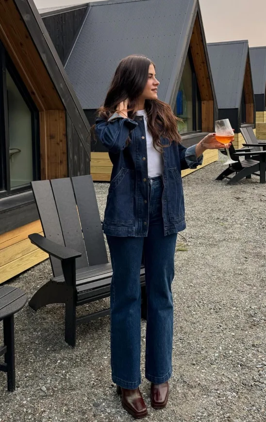Early Fall Outfit featuring a classic double denim look with a dark blue jacket and jeans, styled with a white tee and burgundy boots – perfect for chilly cabin days.