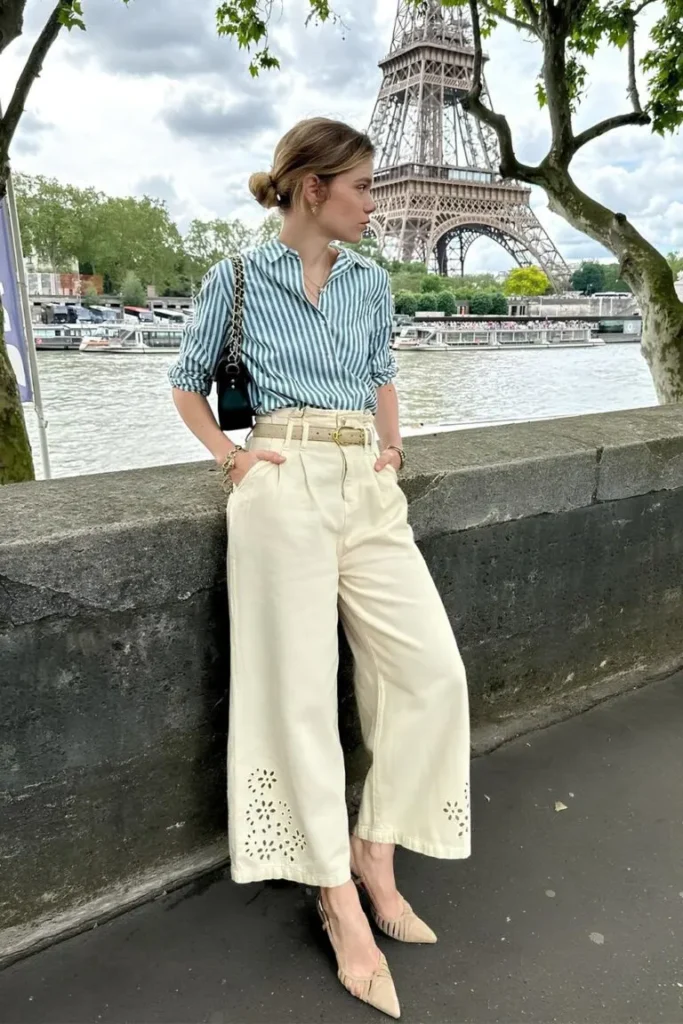 Spring Outfit Ideas featuring a striped button-up shirt tucked into wide-leg cream trousers with eyelet details, paired with pointed heels in Paris.