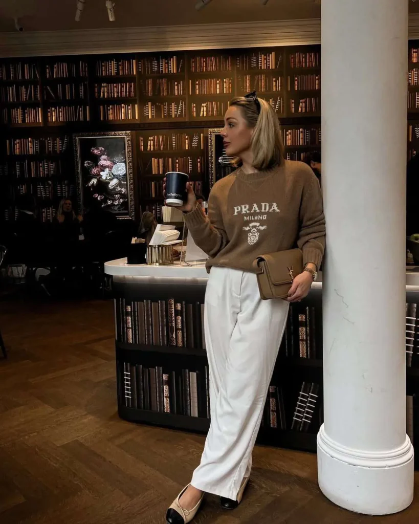 Cozy sweater with branded logo, wide-leg white pants, and beige flats — effortlessly channeling old money for spring.