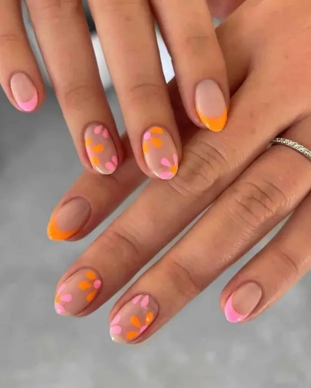 Vibrant and artsy Stunning Nail Ideas featuring orange and pink French tips with abstract flower petal details for a bold statement.