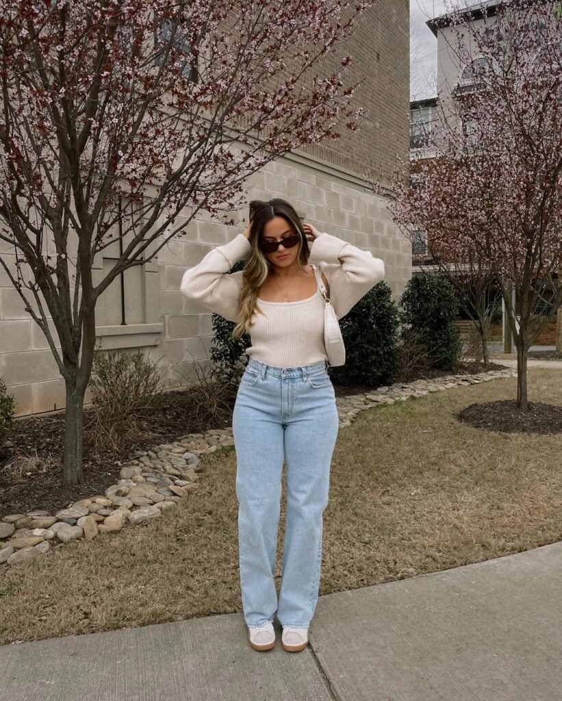 Spring Outfit Ideas with a cozy off-white knit top and high-waisted light blue jeans, finished with white sneakers and slim sunglasses.