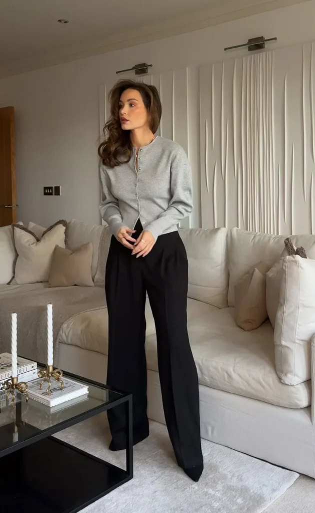 Office outfit in classic neutrals – fitted grey cardigan tucked into high-waisted black wide-leg trousers, styled simply for a comfortable yet elegant workday look.