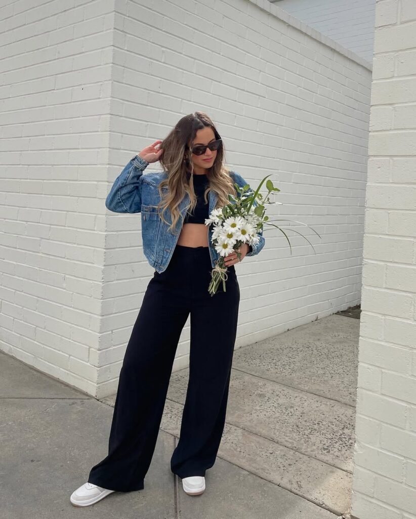 Spring Outfit Ideas with a cropped black top, wide-leg black pants, and a denim jacket, styled with white sneakers and a fresh bouquet.