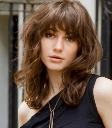 Hairstyles for Medium Length Hair featuring messy natural waves with shaggy layers and full fringe bangs for a relaxed, effortless vibe.