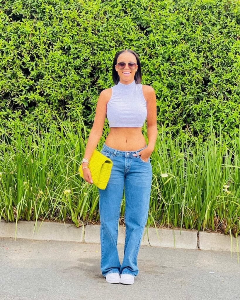 A cute simple outfit with a white sleeveless crop top and classic blue straight-leg jeans, accessorized with a bright yellow clutch for a fun pop of color.