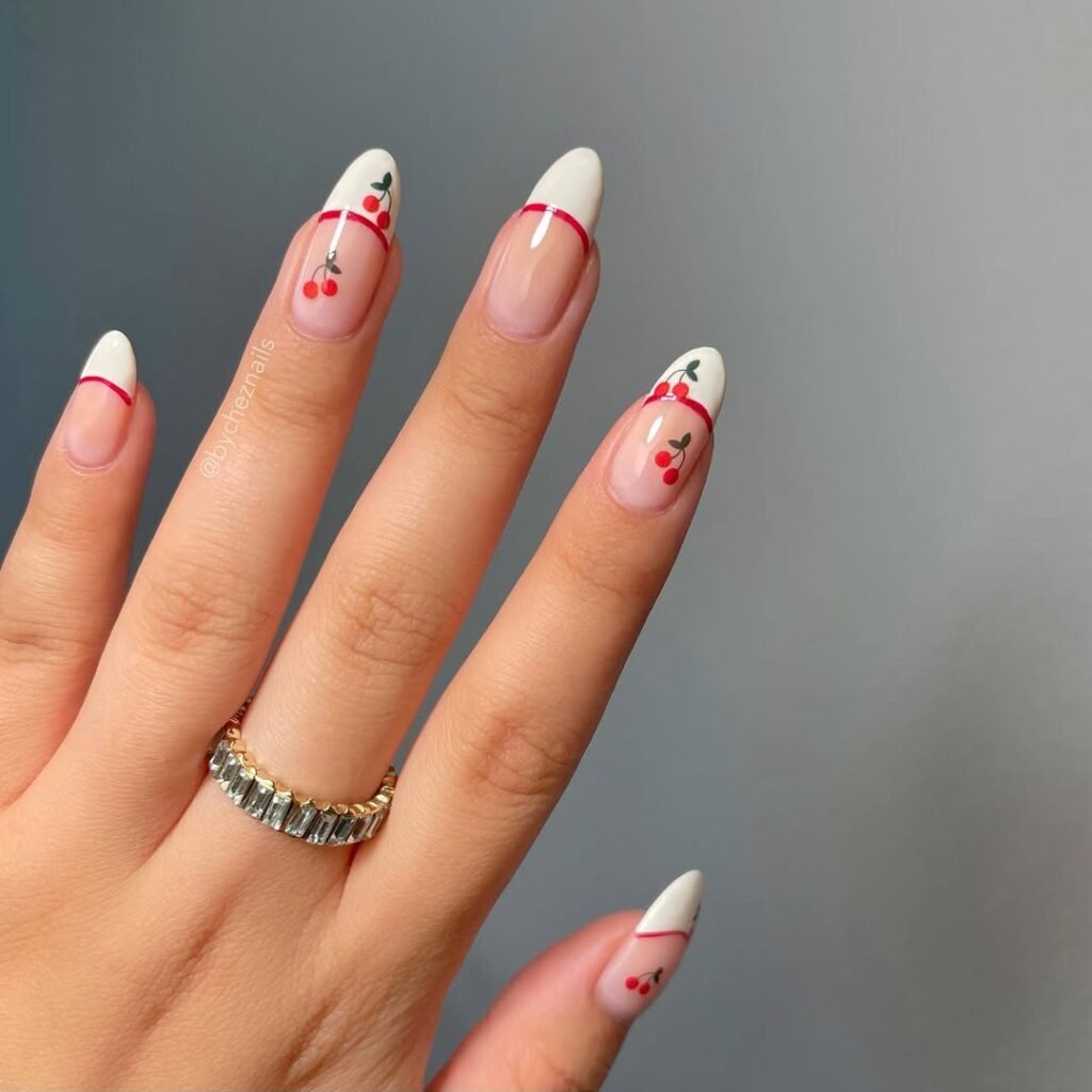 Almond nude nails with crisp white French tips, red stripe detail, and cherry nail art.