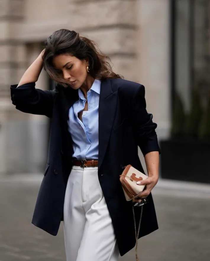 Sophisticated White Pants Outfits featuring tailored white trousers paired with a light blue button-up shirt, navy blazer, and a statement clutch.








