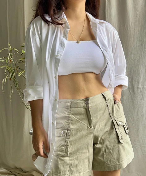 Cargo Shorts Outfits: Effortless cool vibe with light khaki cargo shorts, a white bandeau top, and oversized button-down shirt.