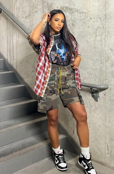 Cargo Shorts Outfits: Bold camo and plaid mix with camo cargo shorts, band tee, plaid shirt, and Nike sneakers.