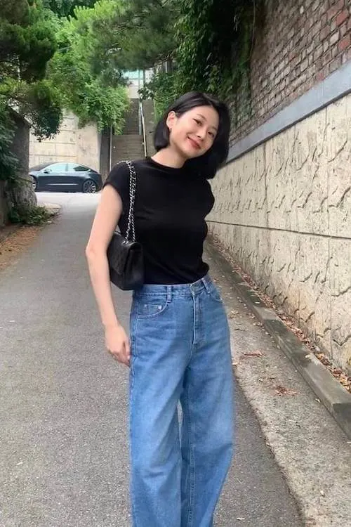 A cute simple outfit featuring a black fitted t-shirt and high-waisted wide-leg jeans, paired with a black shoulder bag for a casual chic look.