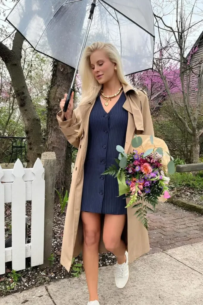 Spring Outfit Ideas with a navy pinstriped mini dress, beige trench coat, and white sneakers, accessorized with a bouquet and umbrella.