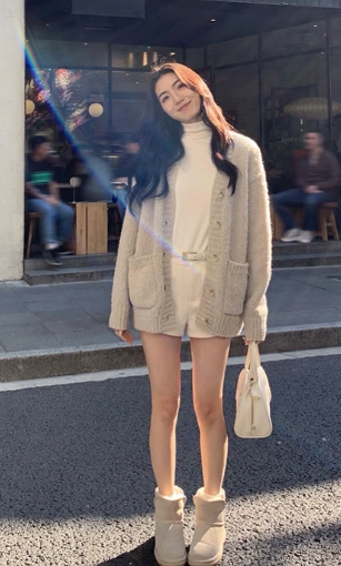 outfit korean style featuring a cream turtleneck romper, oversized beige knit cardigan, matching cream boots, and a white handbag.