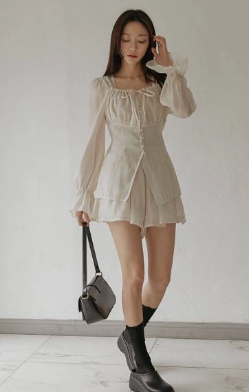 outfit korean style of a light beige mini dress with long sheer sleeves, tiered hem, and paired with black ankle boots.