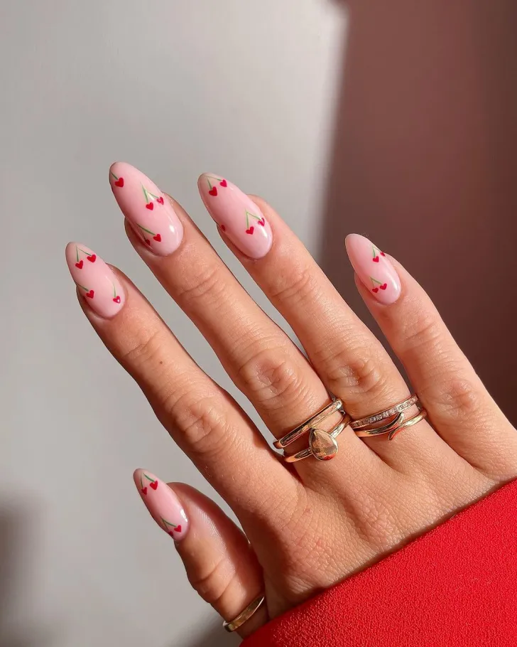 t2.webp – Nude almond nails with minimal cherry nail art featuring small red cherries and green stems