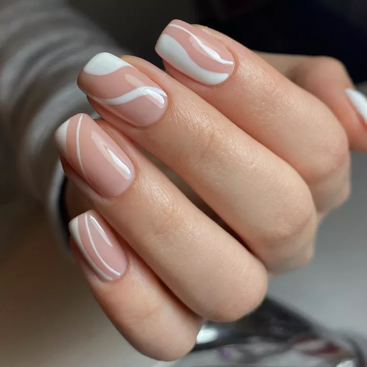 Elegant white swirl nail design over a nude base, offering a chic twist on French tips—perfect for those seeking Stunning Nail Ideas with subtle flair.