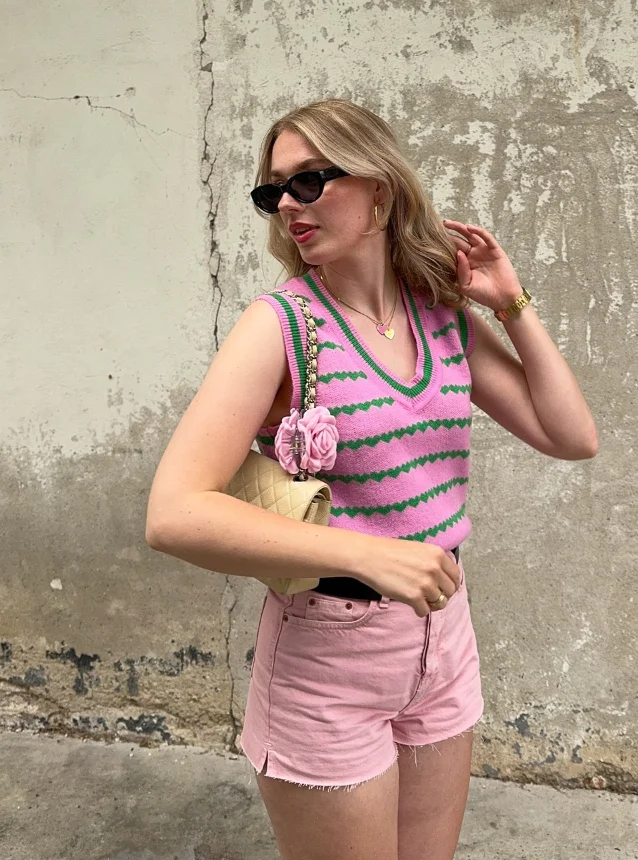 A cute simple outfit in soft pastels – pink striped sweater vest, pink high-waisted shorts, and a quilted cream handbag with floral accents, giving off sweet retro vibes.