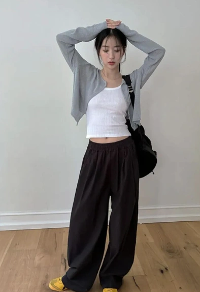 outfit korean style with a cropped white ribbed tank top, light grey cropped cardigan, loose black drawstring pants, yellow sneakers, and a black shoulder bag.