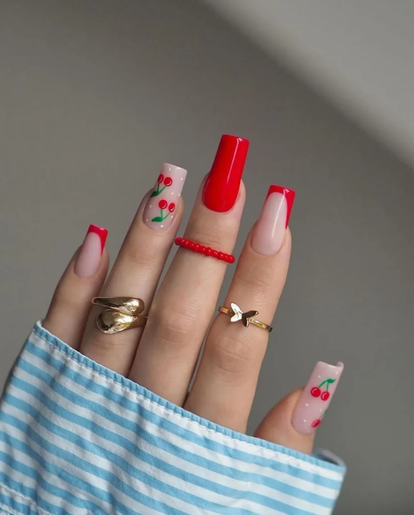 Long square nails with red French tips and accent nails showcasing vibrant cherry nail art.